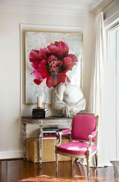 a pink chair sitting in front of a painting