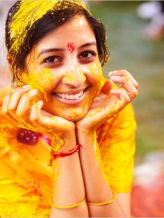 a woman with yellow powder on her face and hands around her face, posing for the camera