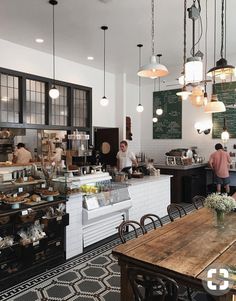 people are standing in the kitchen area of a restaurant with many lights hanging from the ceiling