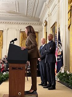 two men and a woman standing at a podium in the middle of a room with other people