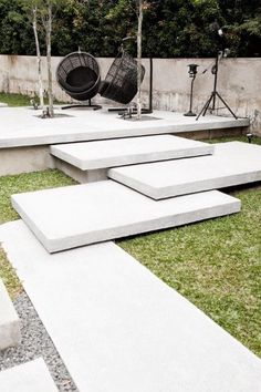 concrete steps are arranged in the middle of a grassy area with chairs and lights on them