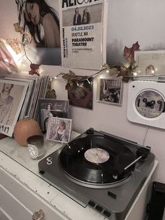 an old record player sitting on top of a dresser next to pictures and other items