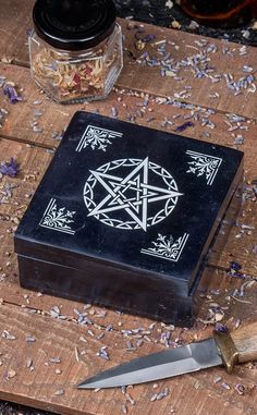 a wooden table topped with a black box and a knife