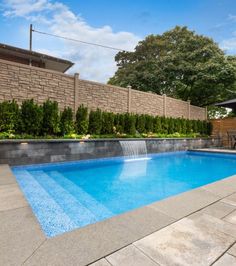 an empty swimming pool in the middle of a backyard with stone walls and landscaping around it