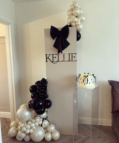 balloons are arranged on the floor in front of a sign that says kelle and is decorated with black, white and silver balloons