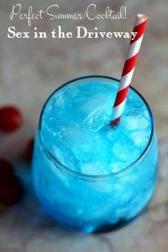 a blue drink with a red and white striped straw sitting in a glass next to a candy cane