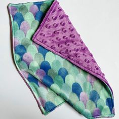 a purple and green polka dot towel folded on top of each other with two different colored dots