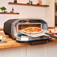 a pizza is being cooked in an open toaster oven on a kitchen countertop