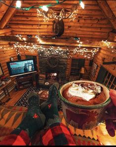 someone is holding up a bowl of food in front of a fireplace with christmas lights on the ceiling