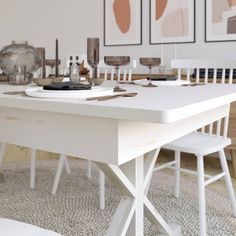 a dining table with white chairs and pictures on the wall