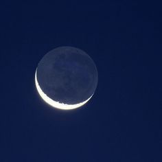 the moon is seen in the dark blue sky