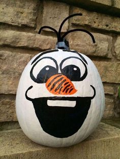 a painted pumpkin sitting on top of a stone wall