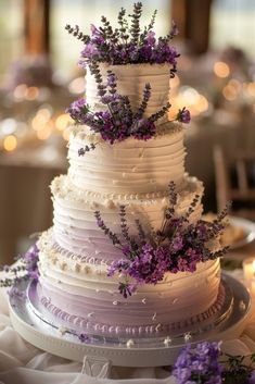 a white wedding cake with purple flowers on top