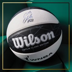 a white and black basketball sitting on top of a green chair with the words wilson written on it