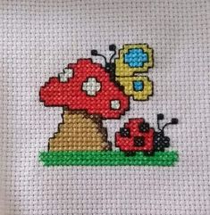 a cross stitch picture with a ladybug and a bug on it's back