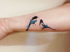 two blue birds on the arm with black outlines and watercolor paint splatters