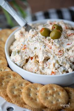 a bowl of dip with crackers and olives