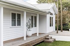 a white house with wooden steps leading up to the front door and side porch area