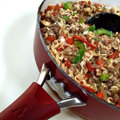 a pot filled with noodles and vegetables on top of a table next to a spatula