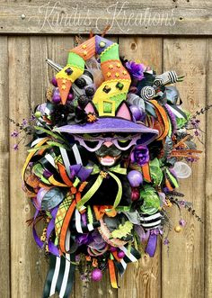 a wreath made out of halloween decorations on a wooden fence with the words happy halloween written above it