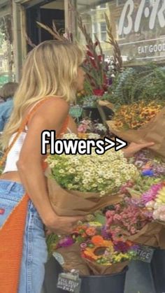 two women standing in front of a flower shop with bags full of flowers and the words flowers > >