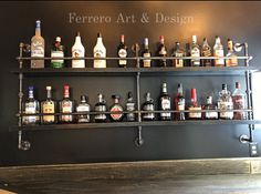 an assortment of liquor bottles are lined up on the wall in front of a sign that reads ferroro art and design