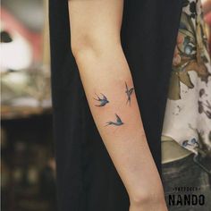 a person with a tattoo on their arm that has two birds flying in the air