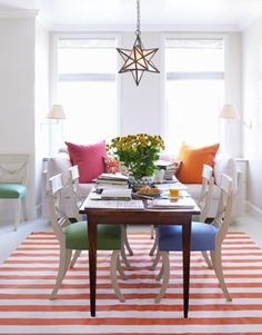 a dining room table with colorful chairs around it