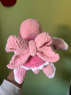 a hand holding a pink crocheted flower