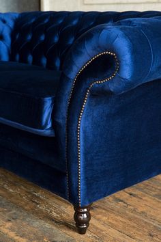 a blue velvet couch with gold studding on the legs