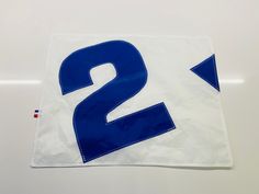 a blue and white number two sign sitting on top of a piece of plastic paper