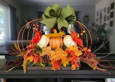 an arrangement of fall leaves, pumpkins and gourds in a birdcage