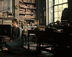 a woman sitting on the floor in front of a book shelf filled with lots of books