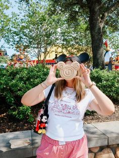 a woman wearing minnie mouse ears looking through her binoculars