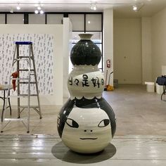 a large white vase sitting in the middle of a room with ladders and chairs