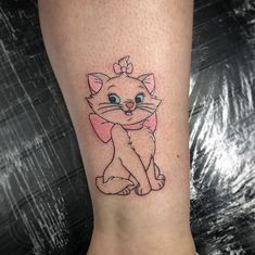 a cat tattoo on the foot of a woman's leg, which has an image of a kitten with a bow around its neck