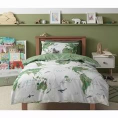 a bed room with a neatly made bed next to a green wall and shelves filled with toys