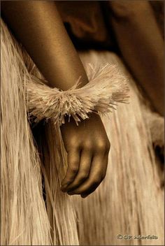 a close up of a person's hand holding something in their left hand and wearing a long, feathery skirt