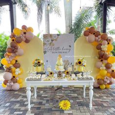 a table with sunflowers and balloons on it