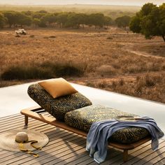 a chaise lounge chair sitting on top of a wooden deck next to an open field