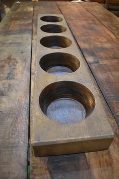 three metal bowls sitting on top of a wooden table with holes in the center and bottom