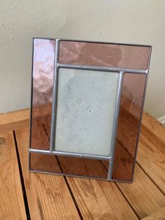 a square mirror sitting on top of a wooden table