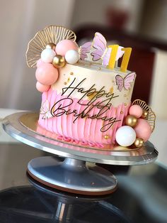 a birthday cake with pink frosting and gold decorations