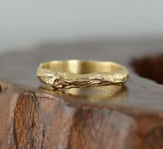 a gold wedding band sitting on top of a wooden block