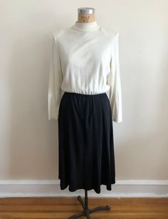 "Cream and black, midi-length knit dress with mock-neck, from the 1980s. The dress measures 21\" (53.5 cm) flat across bust, 13\"-20\" (33-51 cm) flat across waist, and is 49\" (124.5 cm) long. Dress has  shoulder pads. Original size is a 14. 100% acrylic." Noir Color, 1980s Dresses, Black Midi, Knit Midi, Knit Midi Dress, The 1980s, Dress Clothes For Women, Shoulder Pads, Midi Length