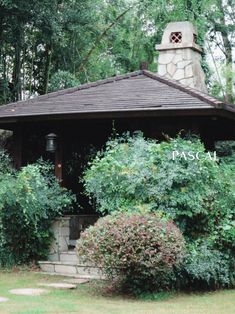 a gazebo surrounded by trees and bushes with a clock on it's roof