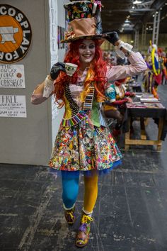 a woman dressed in costume walking down the street with a hat on her head and colorful tights