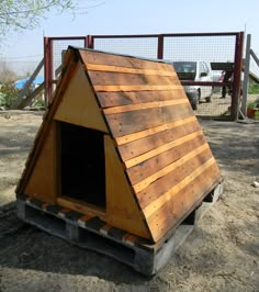 a dog house made out of pallets in the dirt