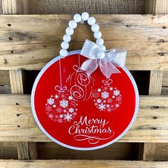 a red and white christmas ornament hanging on a wooden fence with snowflakes