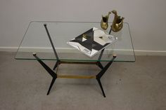 a glass table with two gold vases sitting on it's sides and a book in the middle